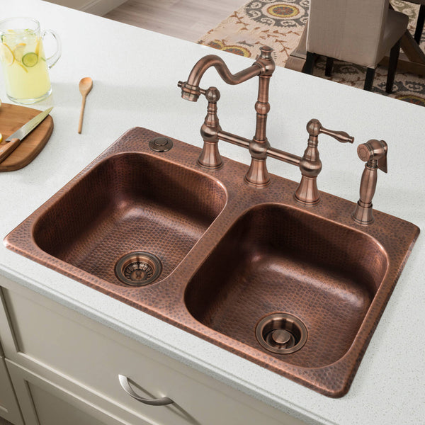 Copper kitchen sink with faucet on a white countertop