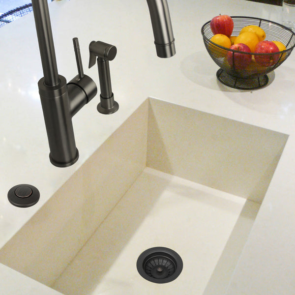 Beige kitchen sink with black faucet and accessories on a white countertop.