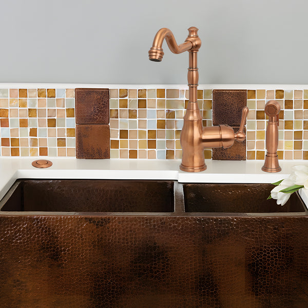 Copper kitchen sink with faucet against a mosaic tile backsplash